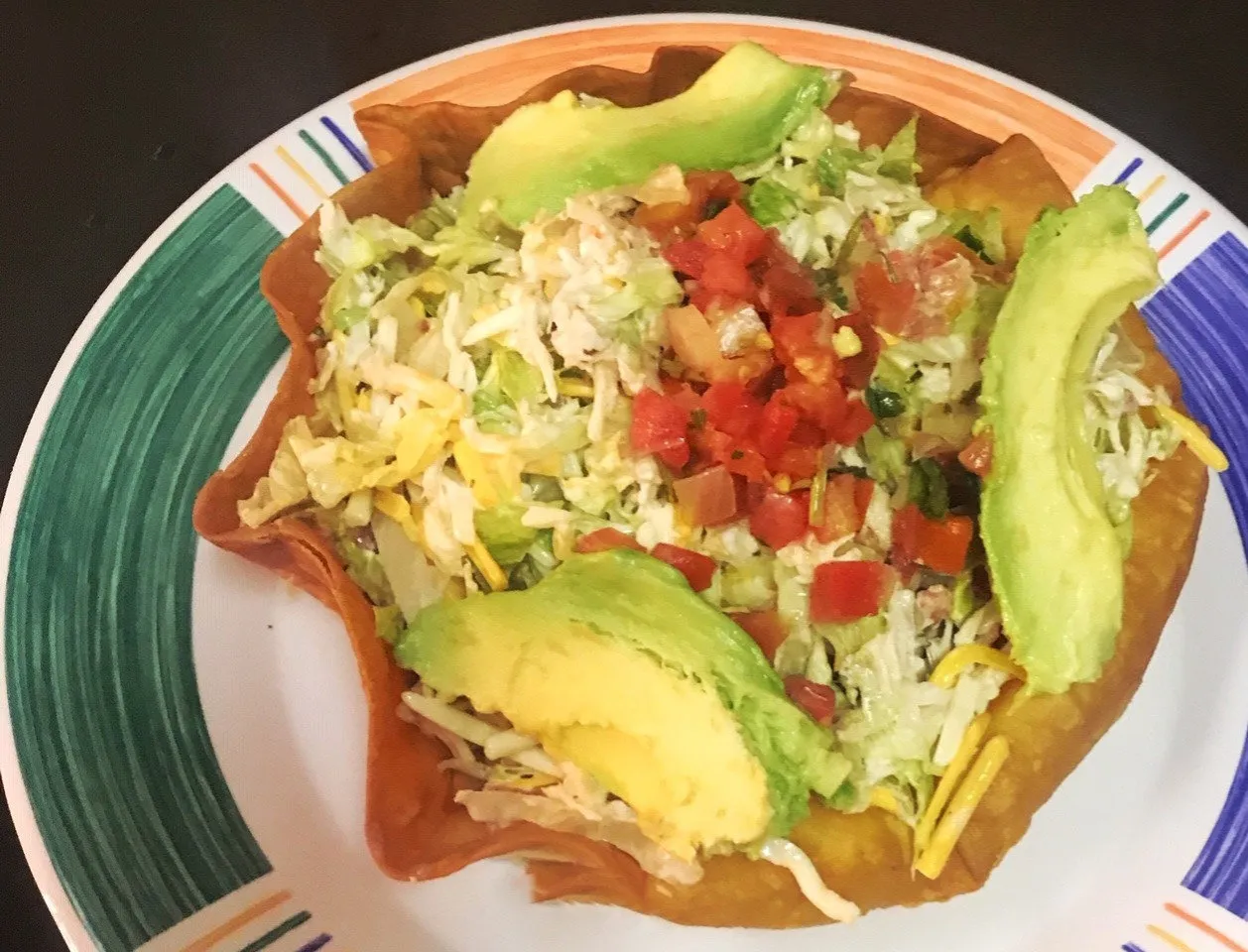 A taco salad in a crispy tortilla bowl with avocado