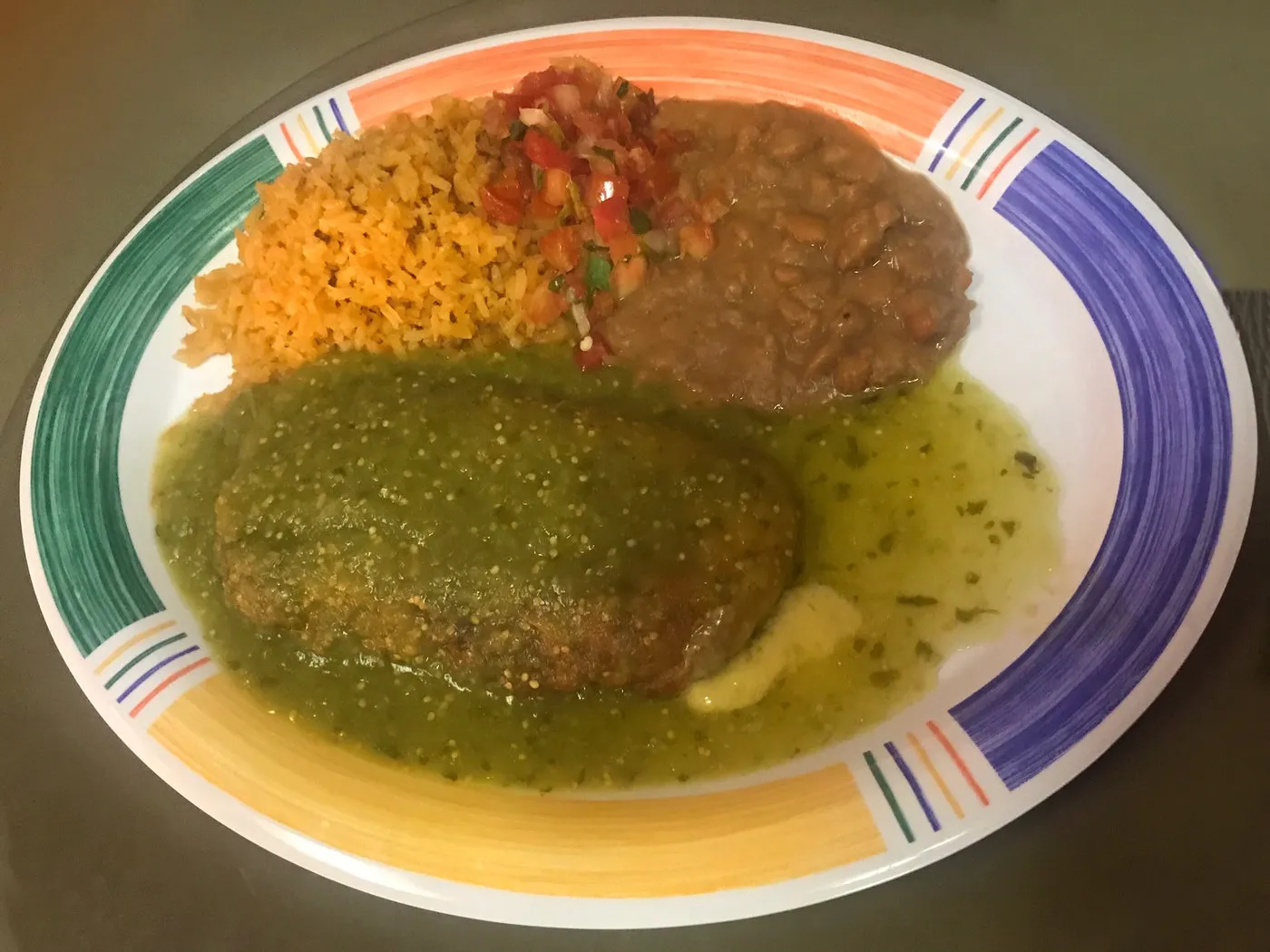 A tamale plate topped with green tomatillo sauce